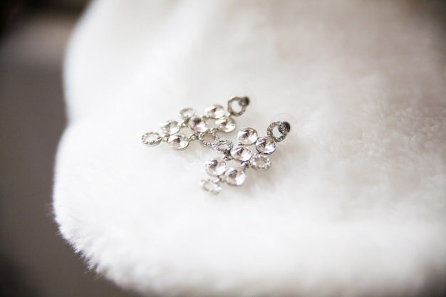 bride-earrings-lie-white-cape-closeup_127746-295
